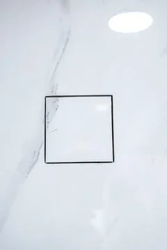 Modern square light switch installed on a white marble tile wall in a luxury Stock Photos