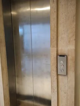 Modern steel elevator on stone wall Stock Photos