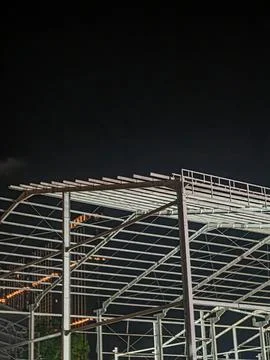 Modern Steel Frame Construction Structure at Night with City Building Lights Stock Photos