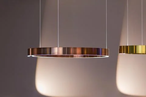 Modern streamlined mirror copper ring chandelier. Metal gold lamp on gray bac Stock Photos