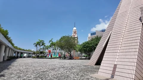 A modern structure with a large entrance faces a clock tower in the city. Palm Stock Footage 287000243