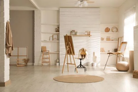 Modern studio interior with artist's workplace and foldable wooden easel near Stock Photos