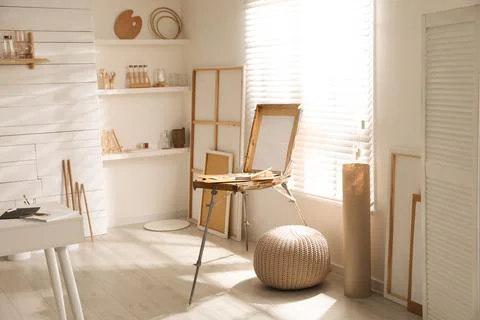 Modern studio interior with artist's workplace and wooden easel near large wi Foto stock