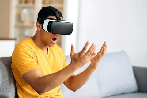 Modern stunned hispanic guy testing VR glasses. A young man uses virtual reality Stock Photos