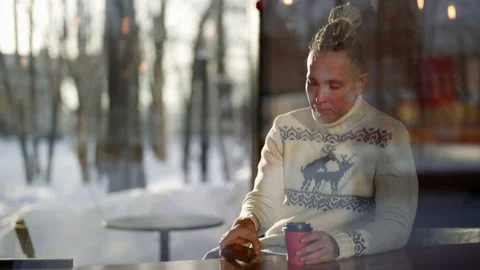 Modern stylish man with dreadlocks is sitting in cafe in winter day and drinking Stock Footage 171182074