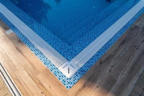 Modern swimming pool corner featuring vibrant blue mosaic tiles, a surroundin Stock Photos