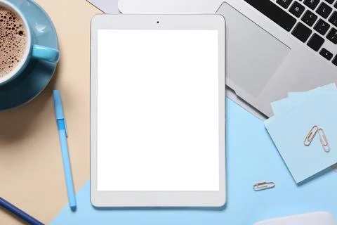 Modern tablet computer with blank screen, cup of coffee and laptop on color b Stock Photos