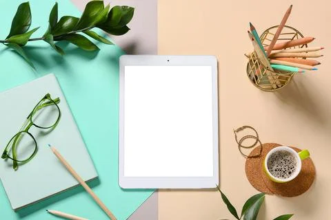 Modern tablet computer with blank screen, cup of coffee and notebook on color Stock Photos