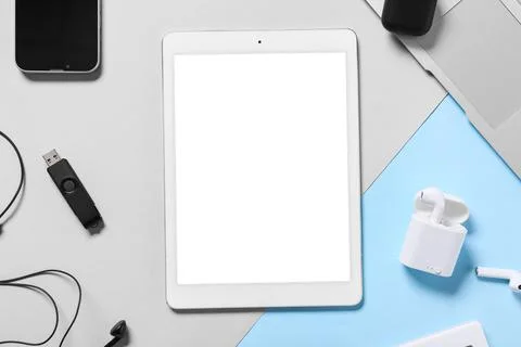 Modern tablet computer with blank screen, earphones and USB flash drive on co Stock Photos