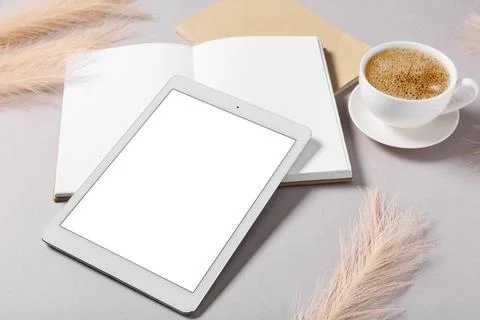 Modern tablet computer with blank screen, notebook and cup of coffee on grey  Stock Photos