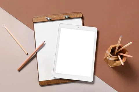 Modern tablet computer with blank screen, clipboard and pencils on color back Stock Photos