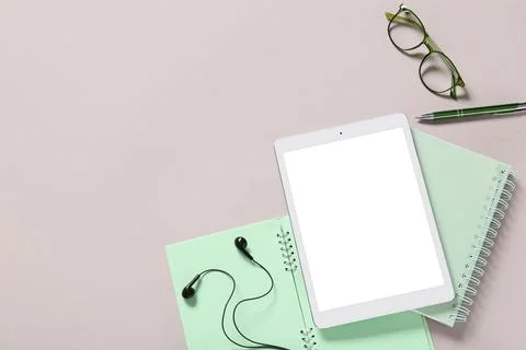 Modern tablet computer with blank screen, earphones and eyeglasses on grey ba Stock Photos