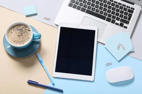 Modern tablet computer with blank screen, cup of coffee and laptop on color b Stock Photos