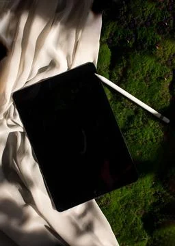 Modern tablet computer resting on a cloth surface beside a decorative object Stock Photos