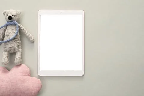 Modern tablet, toy cloud and bear on light background, flat lay. Space for te Stock Photos