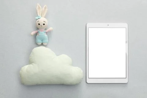 Modern tablet, toy cloud and bunny on light background, flat lay. Space for.. Stock Photos