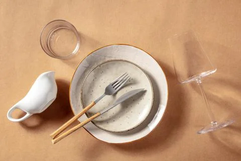 Modern tableware set. Ceramic plates, a wine glass, and cutlery Fotos Stock