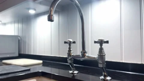 Modern tap dripping with sink and kitchen counter and white wall background Stock Footage 343584941