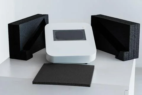 Modern Tech Device with Protective Black Foam Packaging on White Table Foto stock