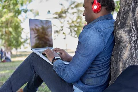 Modern technologies allow a dark-skinned businessman to work anywhere in city Stock Photos