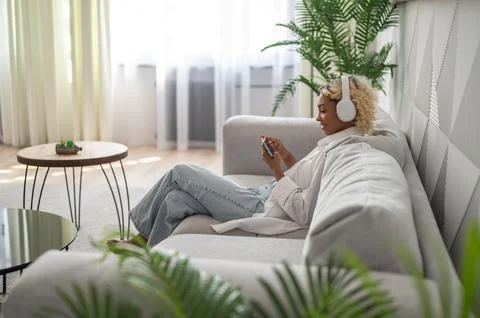 Modern technologies copyspace banner. Happy woman in headphones on the couch Stock Photos