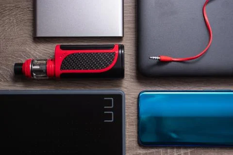Modern technology flat lay, blue smartphone, silver powerbank, black graphic  Stock Photos