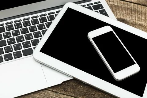 Modern technology setup featuring a laptop, tablet, and smartphone on a wooden Stock Photos