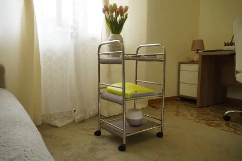 A modern three-tier chrome mobile cart in a cozy living room. Stock Photos
