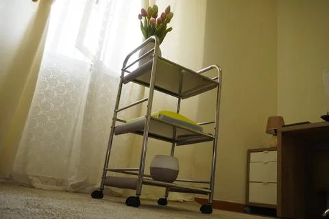 A modern three-tier chrome mobile cart in a cozy living room. Fotos de archivo