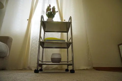 A modern three-tier chrome mobile cart in a cozy living room. 库存照片