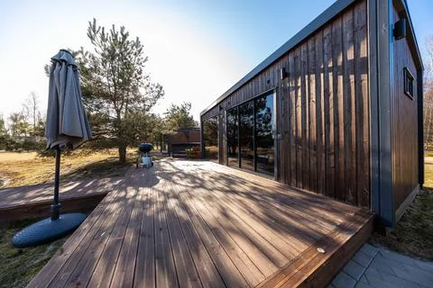 Modern timber cabin with expansive deck in late afternoon light Stock Photos