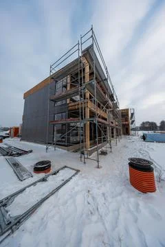Modern timber frame house under cladding in snowy construction site Stock Photos