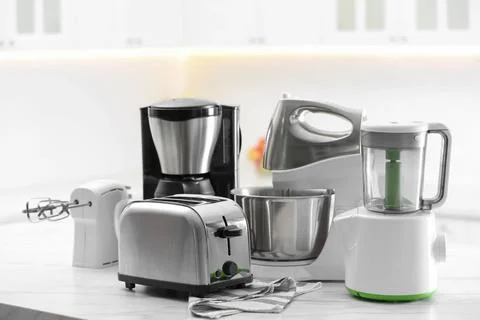 Modern toaster and other cooking appliances on table in kitchen Stock Photos