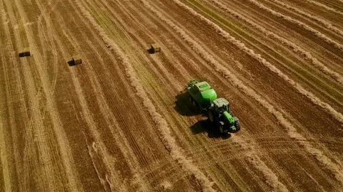 Modern tractor makes haystacks on the field after harvesting. Aerial view. Video stock 89920384