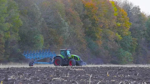 A modern tractor plows the field. Green tractor plows the field. Tractor in the 库存影片 145411292