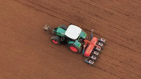 Modern tractor pulling seeder while sowing seasonal crops in prepared field Stock-Footage 334662640
