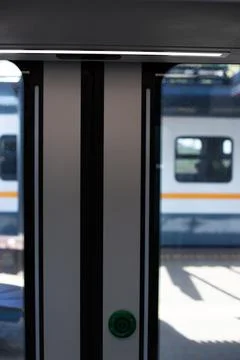 Modern train door with green button for opening. Door is framed by sleek bl.. Photos