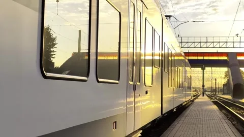 Modern train parked at railway station platform during golden hour, sun Stock-Footage 344095796