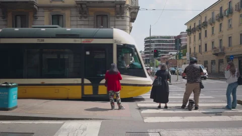 Modern tram departing from stop and crossing intersection in Milan Stock Footage 337372876