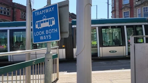 Modern tram passes through a city street with a tramway warning sign Stock Footage 340198683