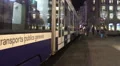 Modern tramcar leaving tram stop, active traffic in city downtown at night HD Footage