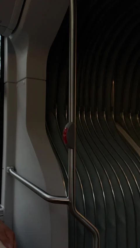 Modern transit handrail with red stop button beside folding ribbed partition Видео 341662897