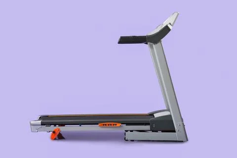 Modern treadmill on lilac background Stock Photos