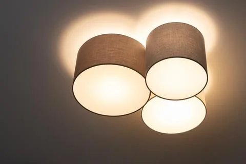 A modern trendy ceiling lamp composed of a group of three cylinders, it shine Stock Photos