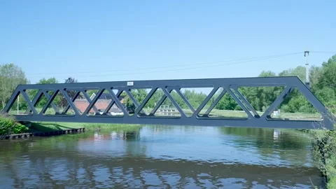 Modern truss bridge crossing a tranquil river on a sunny day Stock Footage 336903052