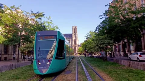 Modern turquoise tram on green grass tracks with Reims Cathedral in the backgrou Stock Footage 339982376