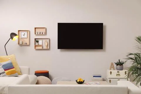 Modern TV, comfortable sofa and decor elements in living room Stock Photos