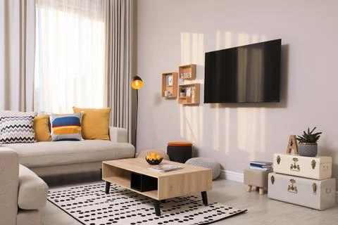 Modern TV, comfortable sofa and decor elements in living room Stock Photos