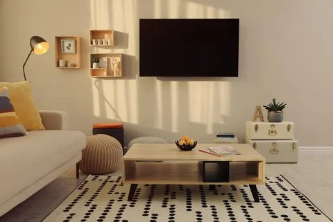 Modern TV, comfortable sofa and decor elements in living room Stock Photos