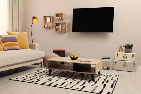 Modern TV, comfortable sofa and decor elements in living room Stock Photos